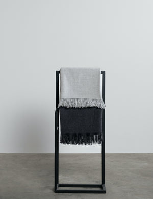 grey and charcoal grey alpaca throws hanging on a rail. 