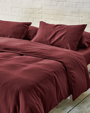 dark red bedding on a made bed.