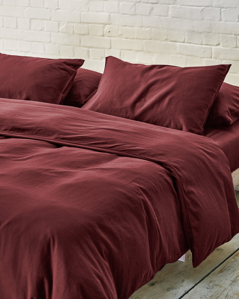 dark red bedding on a made bed.