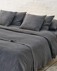 close up of dark grey waffle throw and matching cushions. 