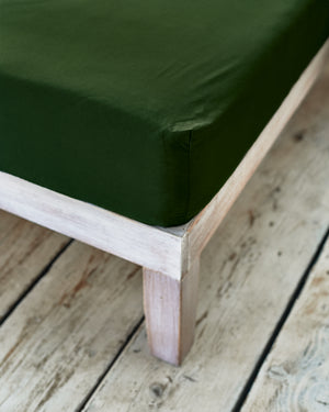 tight fitted corner of dark green cotton bedsheet