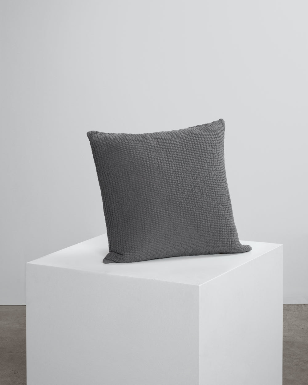 dark grey waffle cushion on cube. 