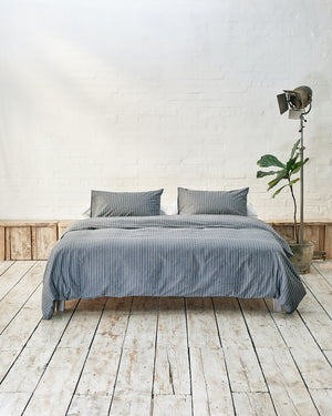 Modern bedroom with navy and white striped bedding and exposed brick wall