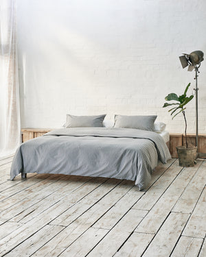 Light grey striped bedding lifestyle shot in a modern airy bedroom. 