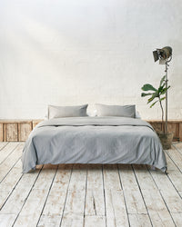 Front facing lifestyle shot of light grey bedding. 