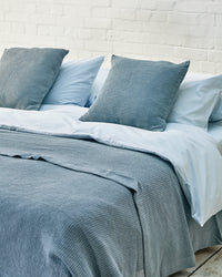 arctic blue waffle scatter cushions with matching throw on a light blue bed. 