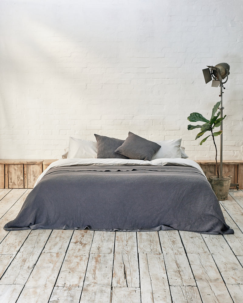 Modern bedroom with light grey bedding set with bedspread and scatter cushions in dark grey