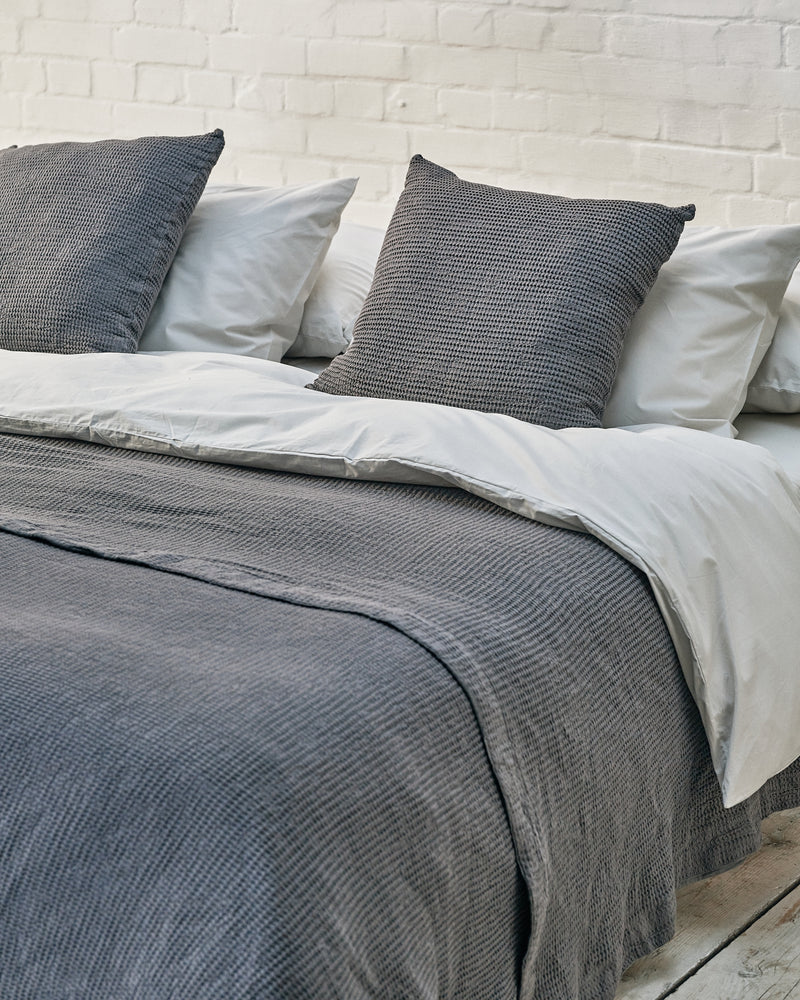 close up of dark grey waffle bedspread and matching scatter cushions. 