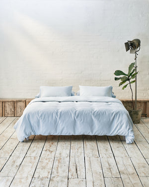 Modern bedroom with light blue bedding and exposed brick wall