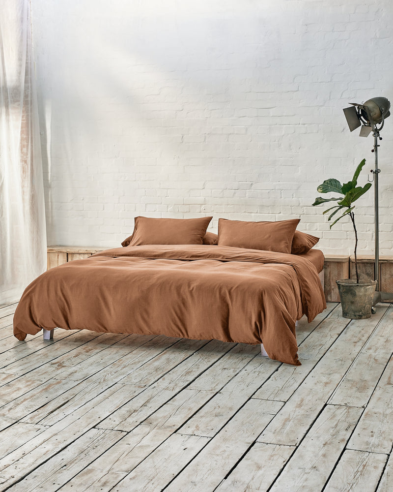lifestyle image of caramel brown in a modern bedroom with rustic wood floors and white walls.