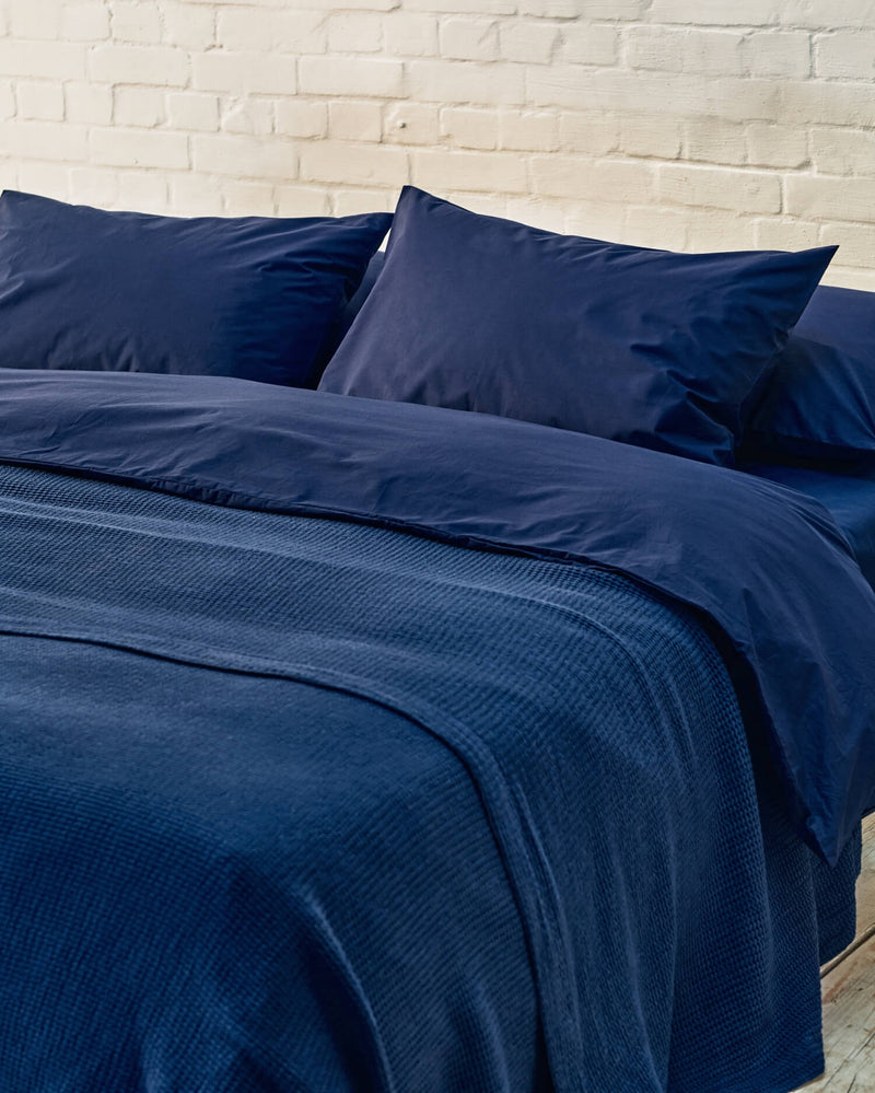 navy bedspread on a dark blue bed. 