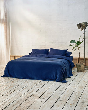 lifestyle image of dark blue bedspread on a navy bed.