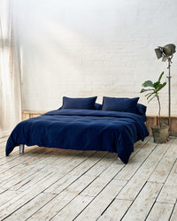 Modern bedroom with navy blue bedding and exposed brick wall
