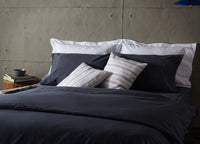 white linen scatter cushion with blue stripes on dark navy bedding