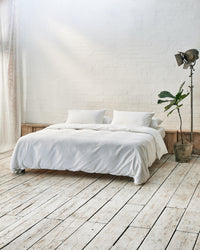 Modern bedroom with white bedding and exposed brick wall